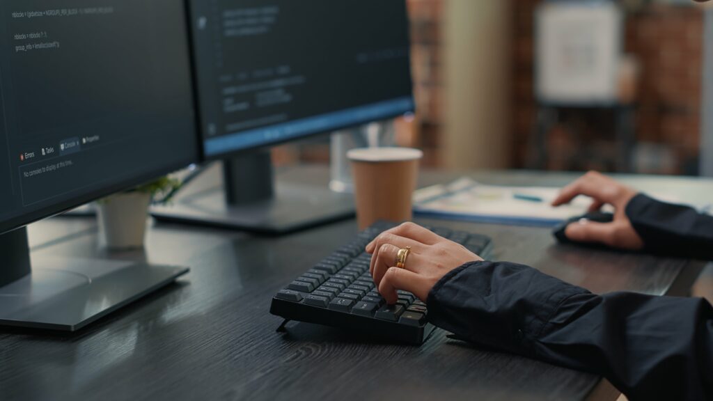 Closeup Developer Hands Typing Code Keyboard While Looking Computer Screens With Programming Interface Software Programmer Sitting Desk With Clipboard Writing Algorithm Min